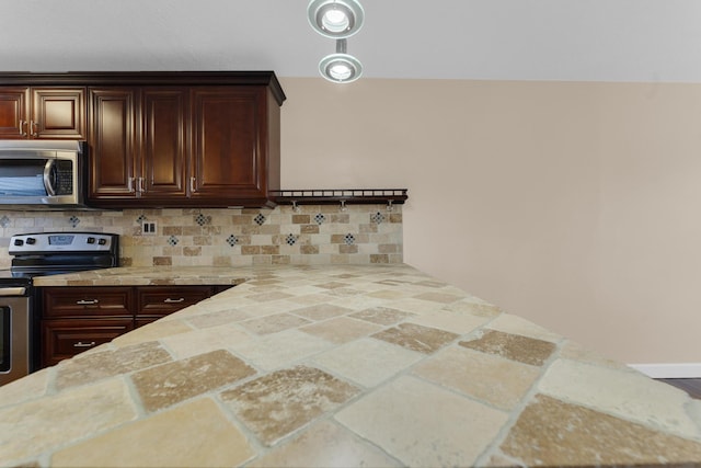 kitchen with dark brown cabinetry, decorative backsplash, and appliances with stainless steel finishes