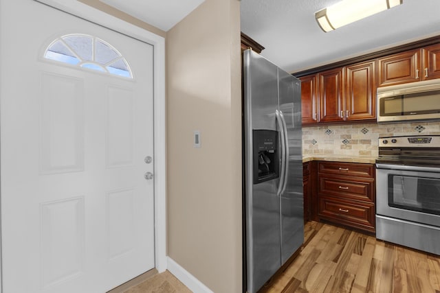 kitchen featuring backsplash, stainless steel appliances, light hardwood / wood-style floors, and light stone countertops