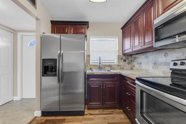 kitchen featuring tasteful backsplash, sink, stainless steel appliances, and light hardwood / wood-style floors