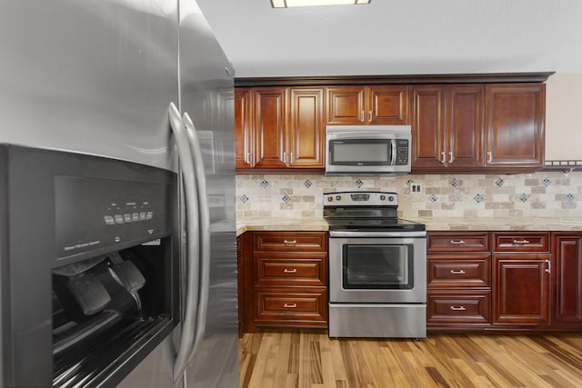 kitchen with light stone counters, stainless steel appliances, tasteful backsplash, and light hardwood / wood-style flooring