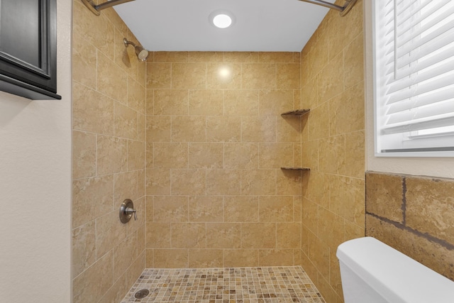 bathroom featuring tiled shower and toilet