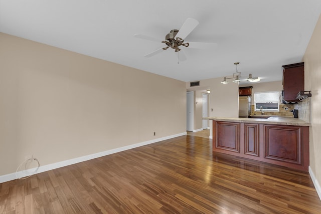 kitchen featuring pendant lighting, dark hardwood / wood-style flooring, decorative backsplash, ceiling fan, and kitchen peninsula