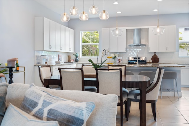 kitchen with stainless steel range, an island with sink, white cabinets, and wall chimney exhaust hood