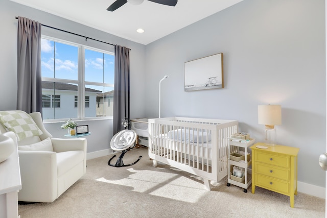 bedroom featuring a crib, light colored carpet, and ceiling fan