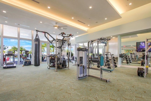 workout area featuring light carpet, a towering ceiling, expansive windows, and ceiling fan