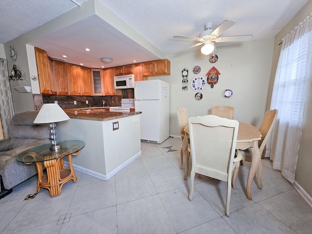 kitchen featuring white appliances, tasteful backsplash, a textured ceiling, light tile patterned flooring, and kitchen peninsula