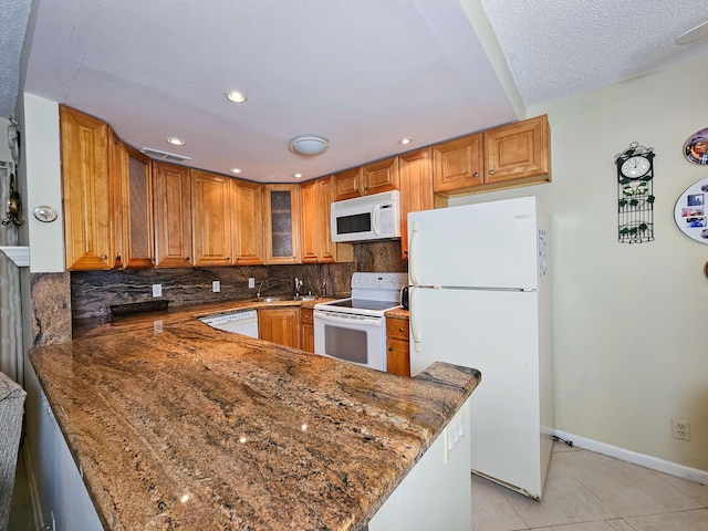 kitchen with light tile patterned flooring, white appliances, kitchen peninsula, and backsplash