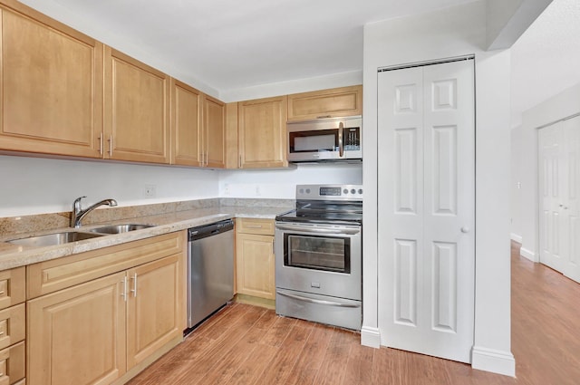 kitchen featuring appliances with stainless steel finishes, light brown cabinetry, sink, light stone countertops, and light wood-type flooring