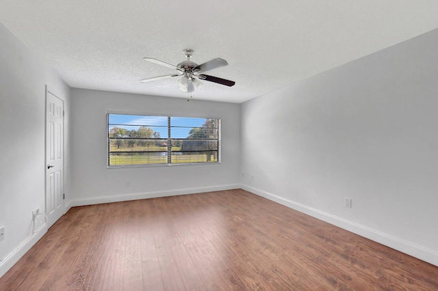 empty room with ceiling fan, wood-type flooring, and a textured ceiling