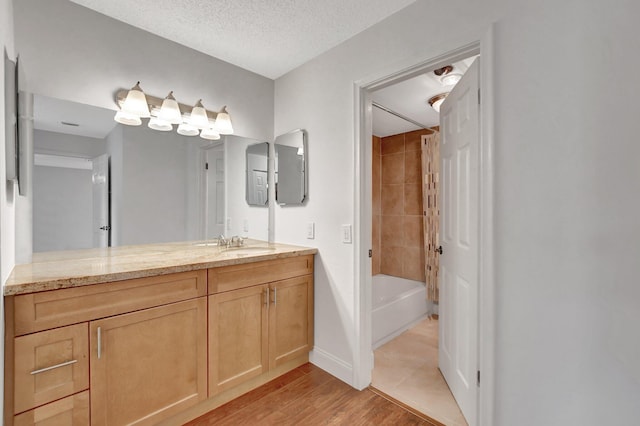 bathroom featuring tiled shower / bath, wood-type flooring, vanity, and a textured ceiling