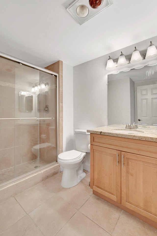 bathroom featuring an enclosed shower, vanity, tile patterned floors, and toilet