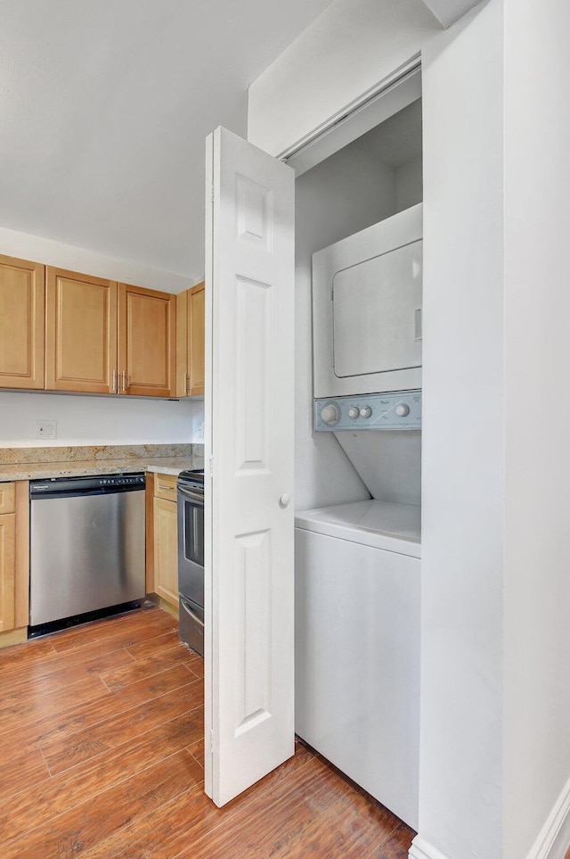 kitchen featuring stainless steel appliances, stacked washer and dryer, light brown cabinetry, and light hardwood / wood-style flooring