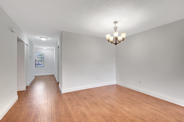 spare room with hardwood / wood-style floors, a notable chandelier, and a textured ceiling