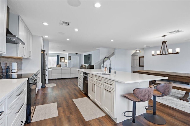 kitchen with white cabinetry, sink, hanging light fixtures, a kitchen island with sink, and stainless steel appliances