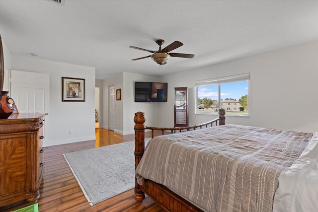 bedroom featuring ceiling fan, wood-type flooring, and a textured ceiling