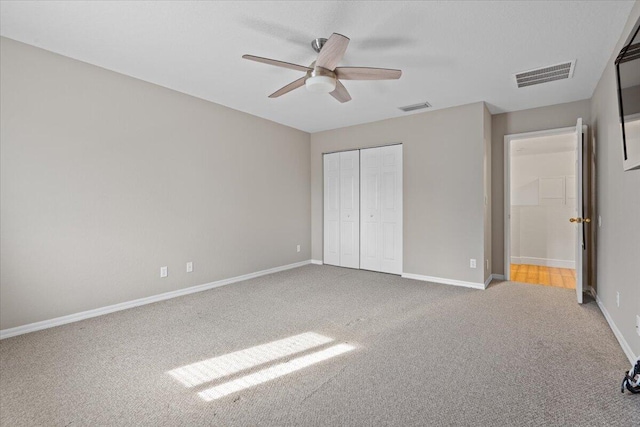 unfurnished bedroom with ceiling fan, light colored carpet, and a closet