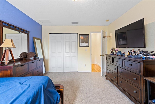 bedroom featuring light carpet, a closet, and a textured ceiling