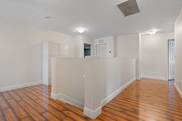 hall with wood-type flooring and a textured ceiling