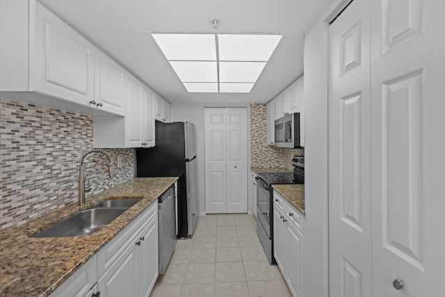 kitchen featuring light tile patterned flooring, sink, white cabinetry, dark stone counters, and stainless steel appliances