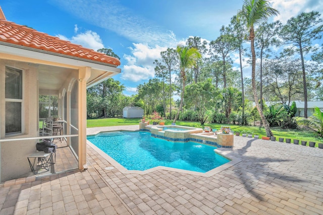 view of swimming pool featuring an outbuilding, a storage shed, a pool with connected hot tub, a lawn, and a patio area