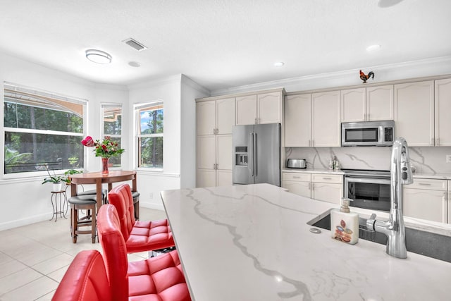 kitchen featuring light tile patterned floors, visible vents, decorative backsplash, appliances with stainless steel finishes, and crown molding