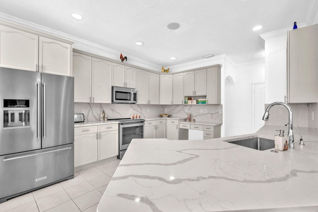 kitchen with light tile patterned floors, appliances with stainless steel finishes, light stone counters, ornamental molding, and a sink