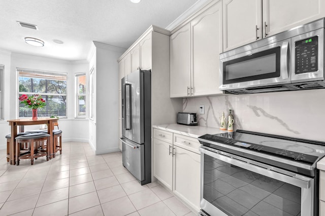 kitchen with visible vents, white cabinetry, stainless steel appliances, and ornamental molding