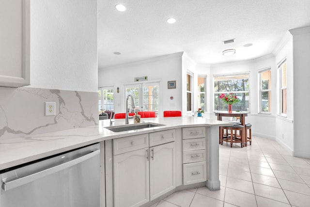 kitchen featuring light tile patterned floors, tasteful backsplash, dishwasher, crown molding, and a sink