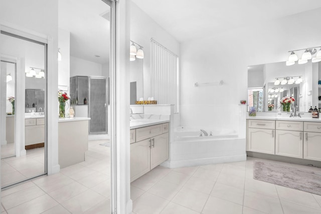 bathroom featuring a stall shower, two vanities, a bath, and tile patterned floors