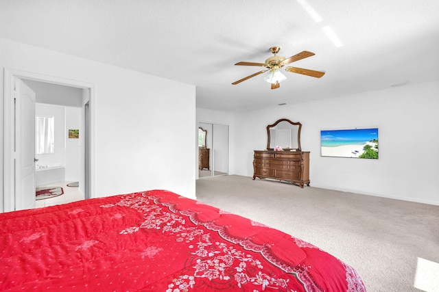 carpeted bedroom featuring ensuite bath and a ceiling fan