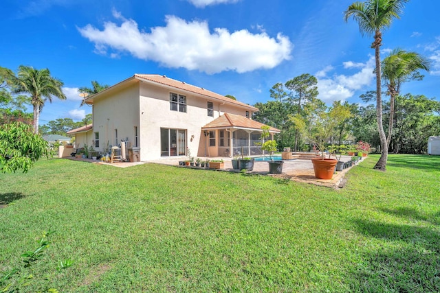 rear view of property featuring a sunroom, a patio area, a yard, and stucco siding