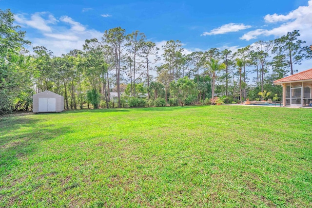 view of yard featuring an outbuilding, a shed, and an outdoor pool