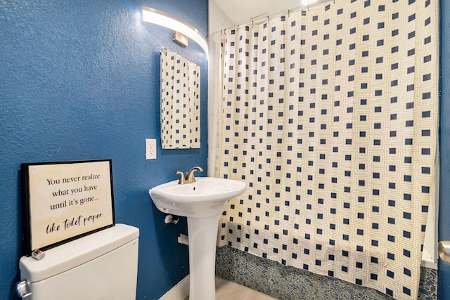 bathroom featuring toilet and curtained shower