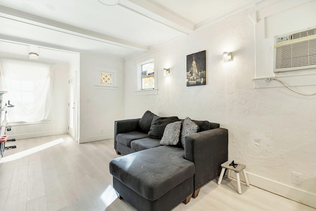 living room with beamed ceiling, a wall unit AC, crown molding, and light hardwood / wood-style flooring