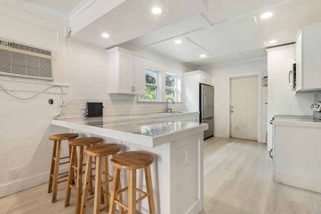 kitchen with white cabinetry, appliances with stainless steel finishes, sink, and a breakfast bar area