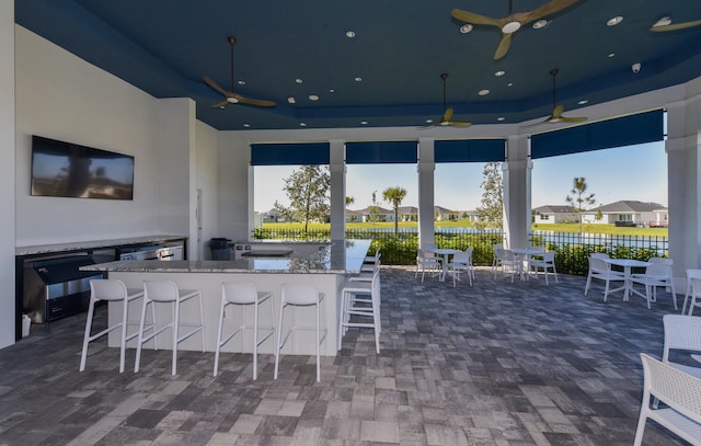 view of patio / terrace featuring a water view, ceiling fan, and exterior bar