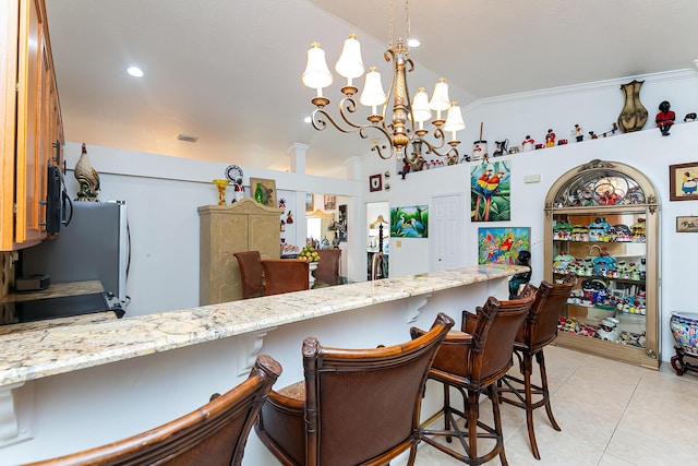 kitchen featuring light tile patterned floors, a kitchen breakfast bar, light stone counters, decorative light fixtures, and kitchen peninsula