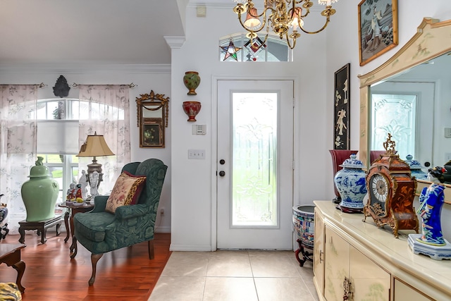 tiled entrance foyer featuring crown molding, a notable chandelier, and a wealth of natural light