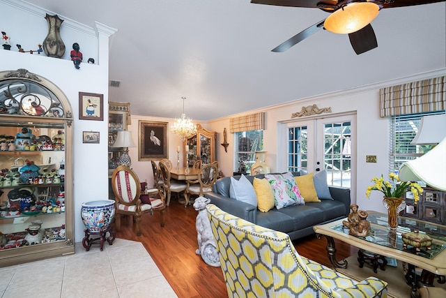 living room with crown molding, light hardwood / wood-style flooring, french doors, and ceiling fan with notable chandelier