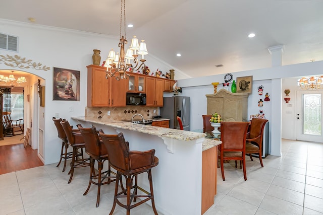 kitchen with stainless steel fridge with ice dispenser, lofted ceiling, backsplash, a notable chandelier, and kitchen peninsula