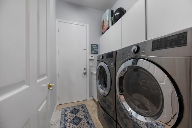 clothes washing area with light tile patterned floors, washer and clothes dryer, and cabinets