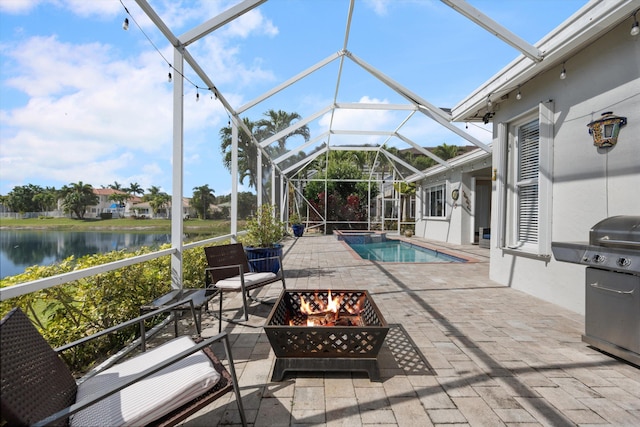 view of pool featuring area for grilling, a lanai, an outdoor fire pit, a water view, and a patio area