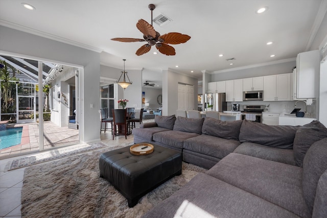 tiled living room featuring crown molding, sink, and ceiling fan