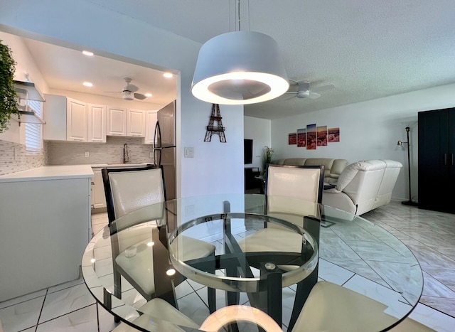 dining area featuring sink, a textured ceiling, and ceiling fan