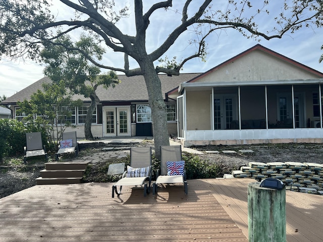 back of house with a sunroom, a deck, and french doors