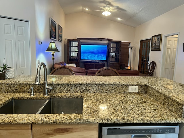 kitchen with lofted ceiling, sink, dishwasher, stone counters, and ceiling fan