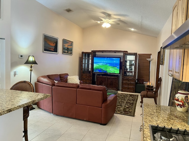 tiled living room featuring ceiling fan, lofted ceiling, and a textured ceiling