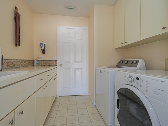 clothes washing area featuring cabinets, sink, washer and dryer, and light tile patterned floors