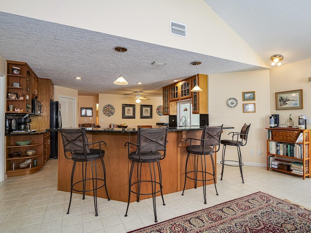 kitchen featuring hanging light fixtures, black fridge, a textured ceiling, and kitchen peninsula