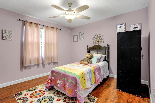 bedroom with ceiling fan, dark hardwood / wood-style flooring, and a textured ceiling